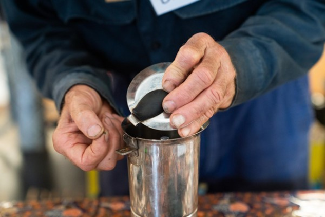 Close up of a person repairing a metal item.